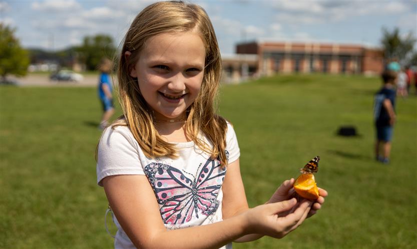 Students smile while releasing butterflies outside